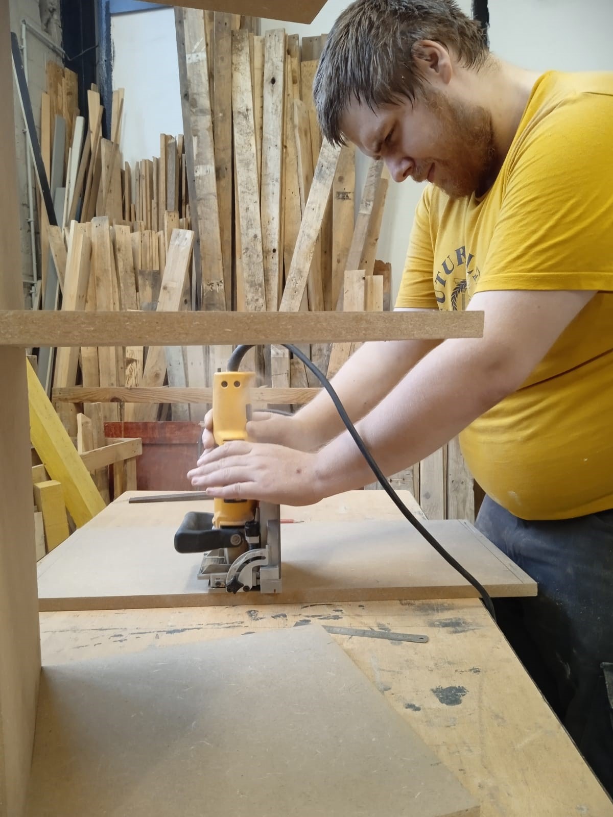 Jeune salarié de l&apos;ACI Premières Heures en Chantier découpant une planche de bois